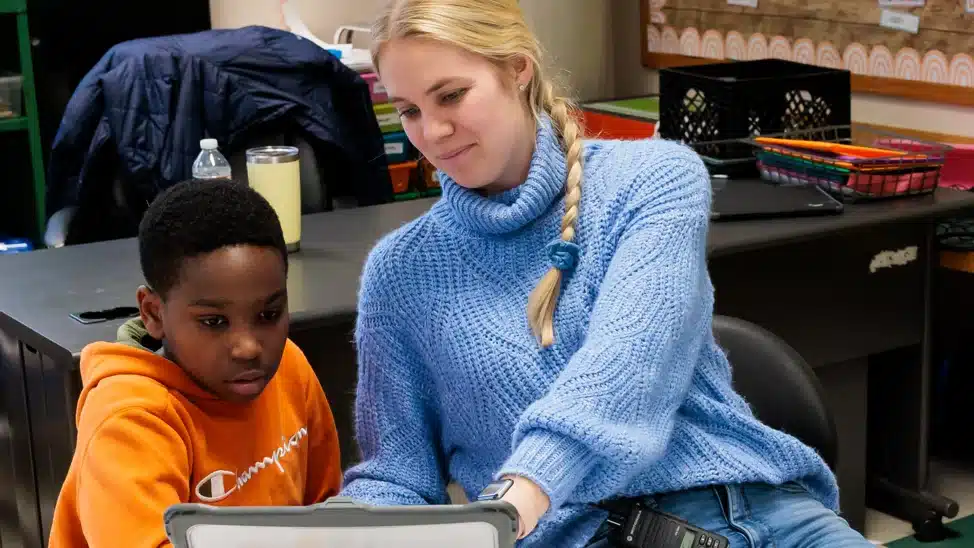 Teacher helping student on their laptop.